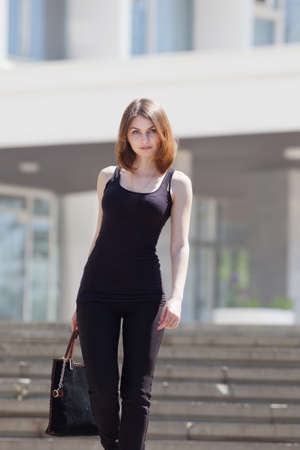 Portrait of attractive young woman outdoors  Slender girl with black bag walking on the stairsの写真素材