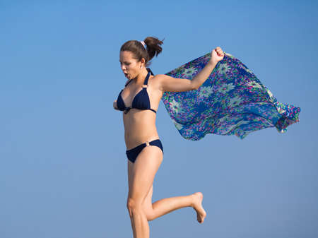 Girl in bikini on open air. Young woman with pareo runs against the skyの写真素材