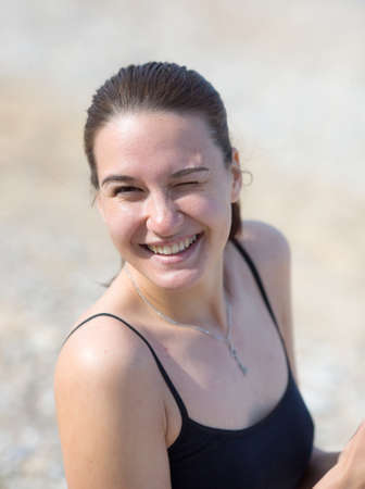Portrait of attractive young woman on open air. Girl looking at camera winks and smilesの写真素材