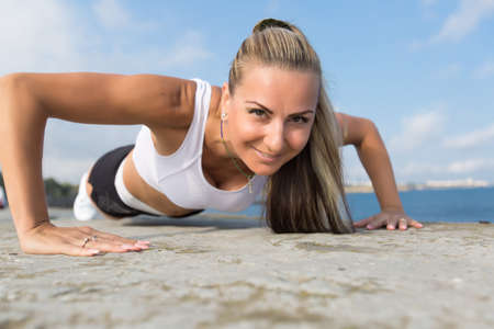 Female doing exercises on open air. Middle age woman doing push ups outdoors.