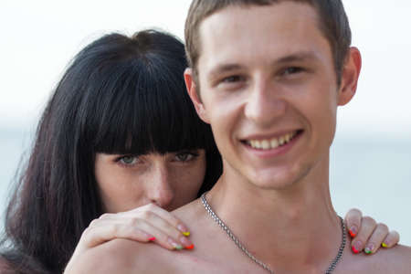Attractive couple at the sea. Young woman hids behind her boyfriend