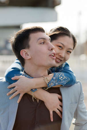 Piggyback. European guy carrying on shoulders his asian girlの写真素材