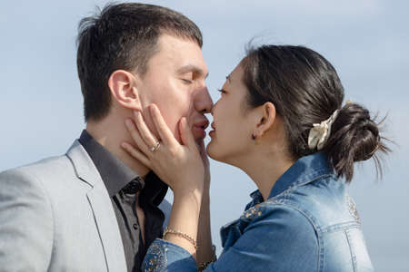Asian girl and european guy kissing on open air. Korean girl embrasing and kissing her european...