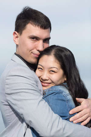 Attractive couple on open air. European guy embracing Korean girlの写真素材