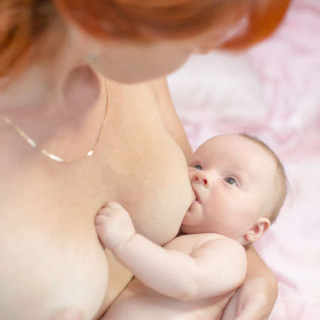 Breastfeeding. Red haired mother holding newborn baby and breastfeedの写真素材