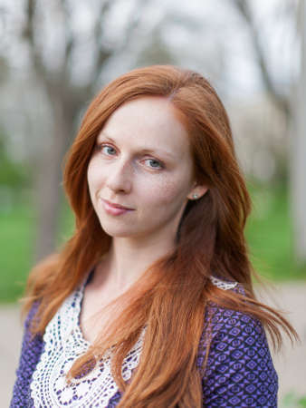 Portrait of ginger girl outdoors. Red haired young woman looking at camera smilingの写真素材