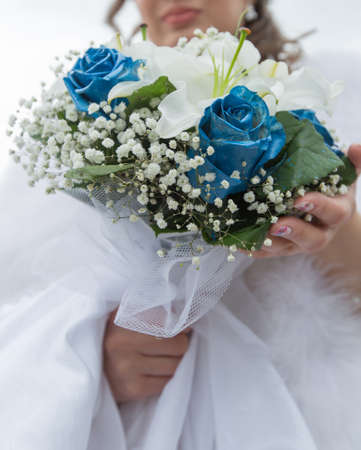 Bridal bouquet. Beautiful bridal bouquet from white lilies and artificially colored roses in hands of brideの写真素材