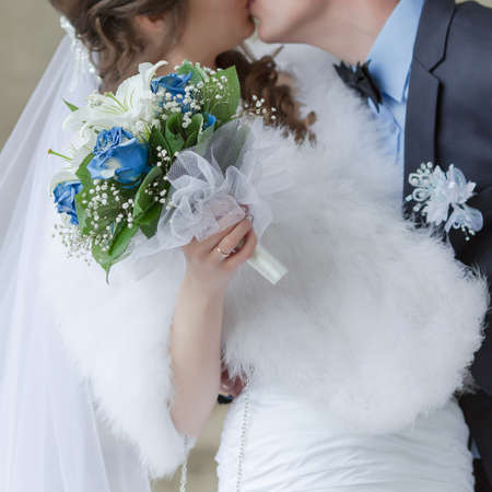 Bridal bouquet. Beautiful bridal bouquet from white lilies and artificially colored roses in hands of brideの写真素材