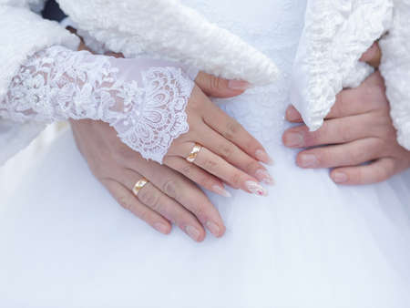 Wedding hands. Hands of newly wedded with wedding rings on fingers against white wedding dress