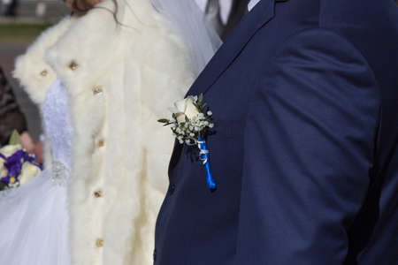 Boutonniere on groom's wedding jacket. Wedding boutonniere from white rose and lot of small flowers on suit of groomの写真素材