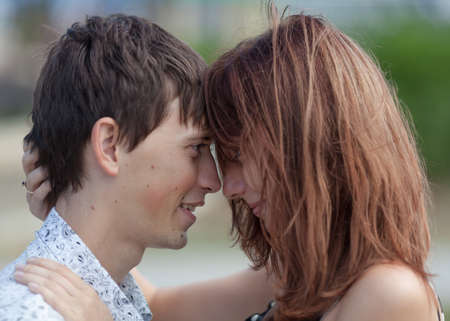 Young couple flirting outdoors. Girl and her boyfriend posing head to head