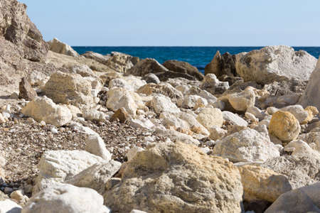 Crimean seascape with rocky beach, strewn with large pebbles. White rocks, stones and pebbles highlight the blue of the Black sea in the backgroundの写真素材