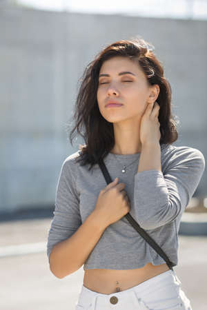 Late-teens girl walking in town in morning time. Waist-up portrait of eighteen-year-old girl with eyes closedの写真素材