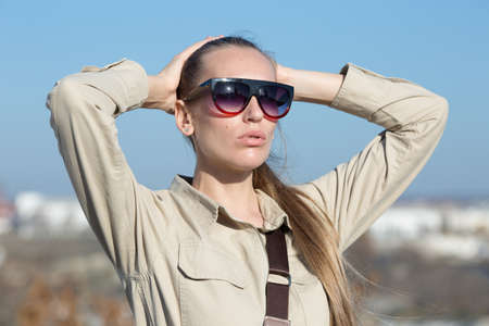 Portrait of blonde person in sunglasses outdoors. Attractive young woman in overalls similar to the...