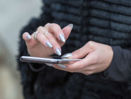 Girl uses smartphone outdoors. Woman's fingers on touchpad gadgetの写真素材