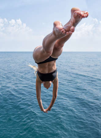 Girl at the sea. Young woman in black swimsuit plunging into deep water of the seaの素材 [FY310151546000]