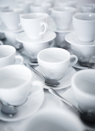 Stacked coffee and tea cups on saucers with silver teaspoonsの写真素材