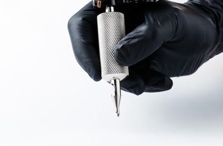 Tattooist makes a tattoo. Closeup,Tattoo artist at work Machine for tattoo on white backgroundの写真素材