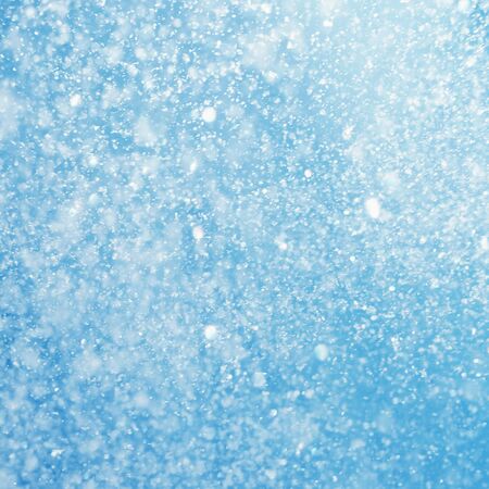 falling snow on the blue snowflakes blurred backgroundの写真素材