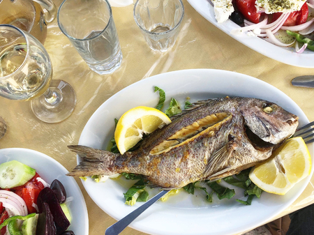 Grilled fish with lemon and vegetables on the plate