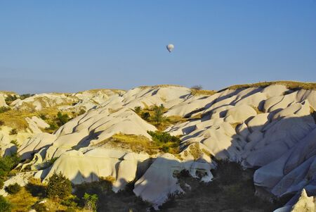 Hot air balloons flying over the peculiar geological formations of Cappadociaの写真素材