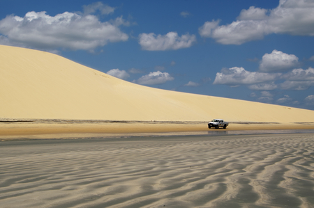 JERICOACOARA, BR - CIRCA AUGUST 2011 - Car on the beach during the low tide, under the big duneのeditorial素材