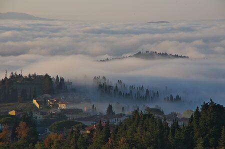 Tuscany hills with autumn colours, fog in the valleys and view of Fiesole.の写真素材