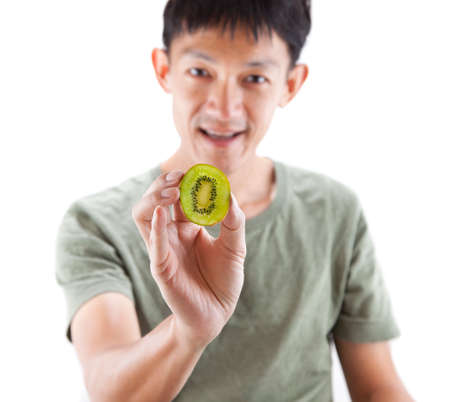 Young man holding the fresh kiwi on white background の写真素材