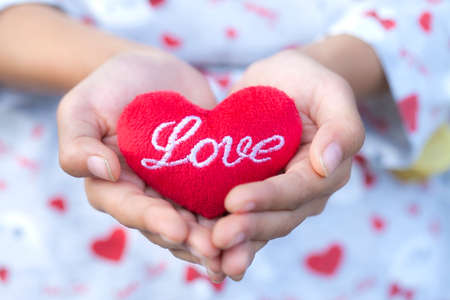 Gir holding red heart pillow in hands,Red heart.の写真素材