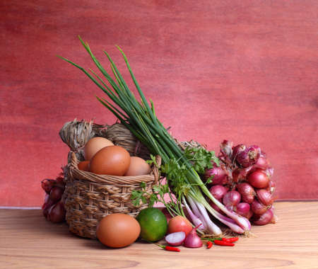 Still life kaffir lime leaf, lemon, lemongrass, galangal, chili,onions eggs and herb and spicy ingredients Thai food (tom yum)over chopping block on wood background. Low key picture style.の写真素材