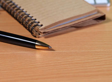 Pen with notepad on wooden table.