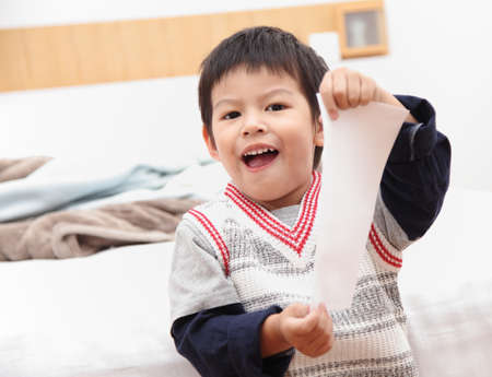 Asian boy show white paper in the bedroom.の写真素材