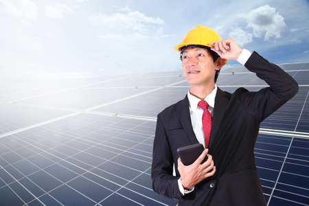 Solar panels. Young engineer man standing in front Solar energy.Power plant using renewable solar energy on blue sky cloud with ray background.の写真素材