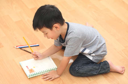 cheerful smiling boy holding a bright colorful picture painted colors in classroom.の写真素材