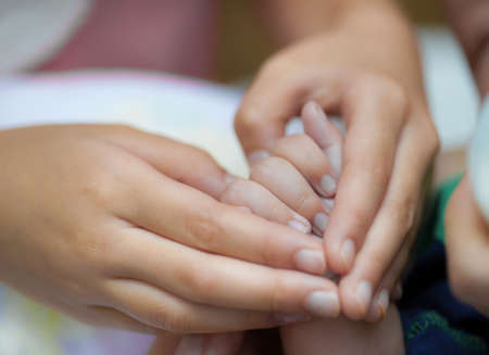 Hand holding a baby hand extreme close-upの写真素材