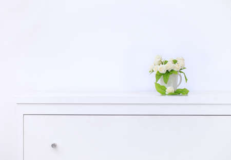 artificial jasmine flower in the pot at the white table with the white wall background.の写真素材