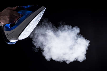 Modern iron  blowing off steam on black backgroundの写真素材