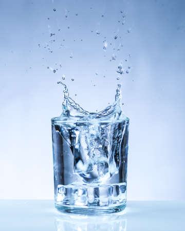 ice cube falling into a glass of waterの写真素材