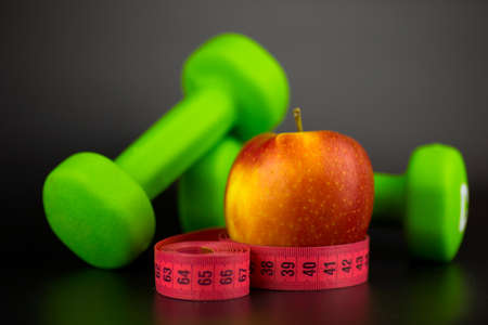 dumbbells, red apple and measure tapeの写真素材