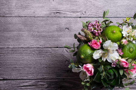 bouquet of roses, limes, aloe and alstromeria on wooden deskの写真素材