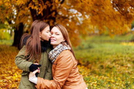 Happy family mother and child little daughter playing on autumn walk. Happy family. The school holidays.の写真素材