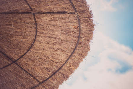Beach umbrella of dried leaves near the sea. Travel vacations concept.の写真素材