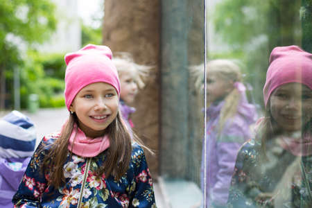 Beautiful kid girl with long hair in rose cap smiling outdoors. Closeup bright portraitの写真素材