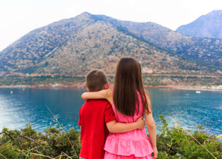 Girl and boy together outdoors. small brother embracing older sister near the sea.の写真素材