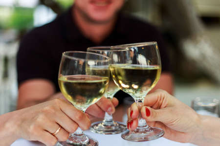 Pouring white wine into the glass against wooden table. Romantic dinner.の写真素材