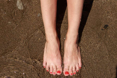 feet in water, female feet in the sand sea.