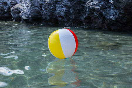 Large colorful beach balls on the water in the sea by the beach. Holidays, travel, vacation and happiness concept.の写真素材