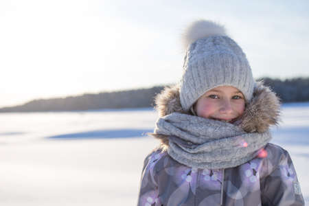 Winter portrait of happy little girl wearing knitted hat and scarf. Family fashion concept.