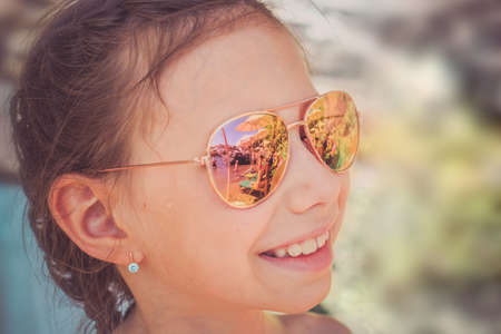 Beautiful young girl in sunglasses with beach reflection. Holidays, travel, vacation and happiness...