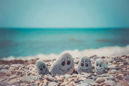 Group of stones with drawn faces in the sand. Father, mother, daughter and son. Concept of happy familyの写真素材